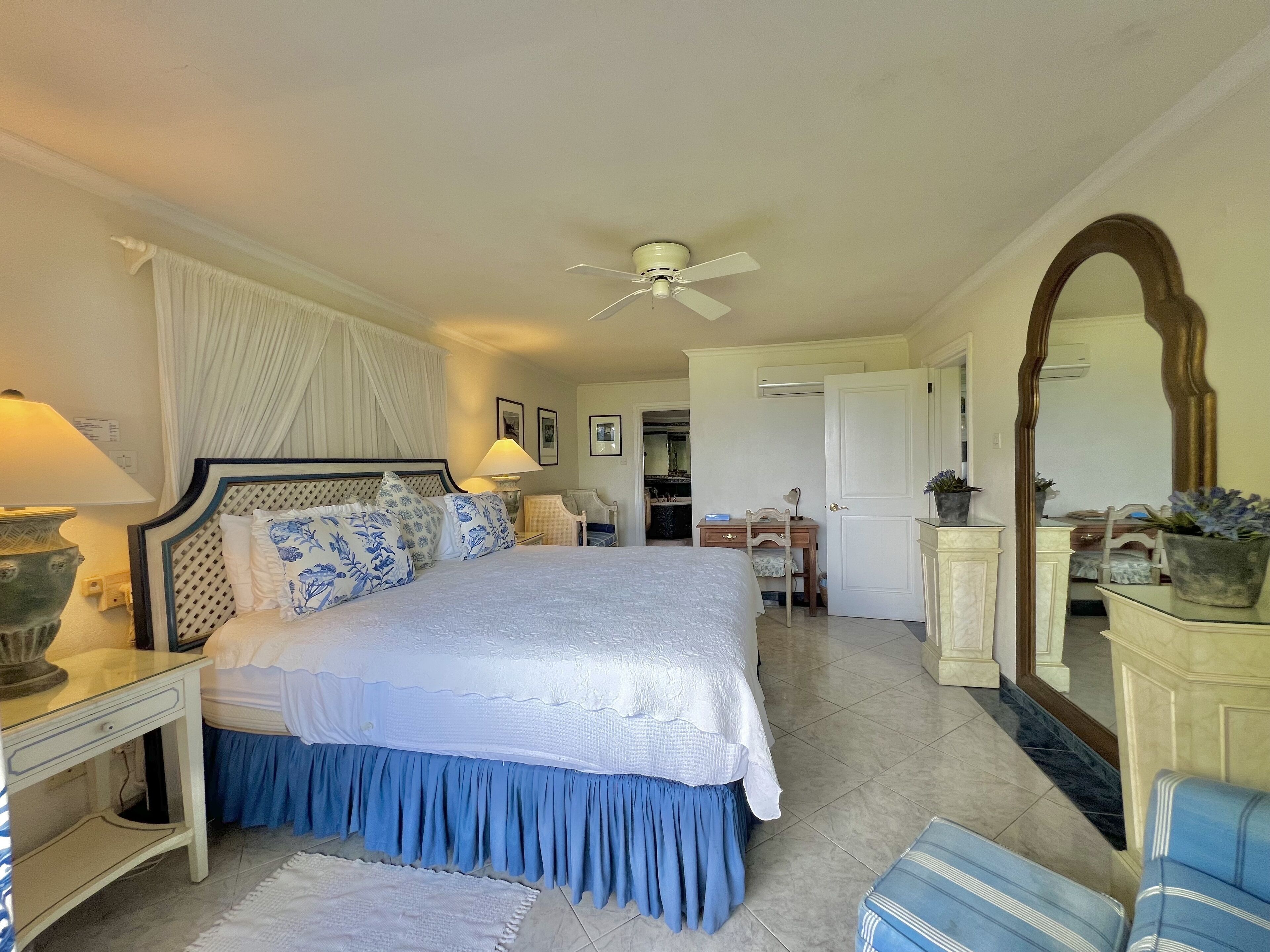 A bedroom with a bed, bedside table, lamp, and a ceiling fan.