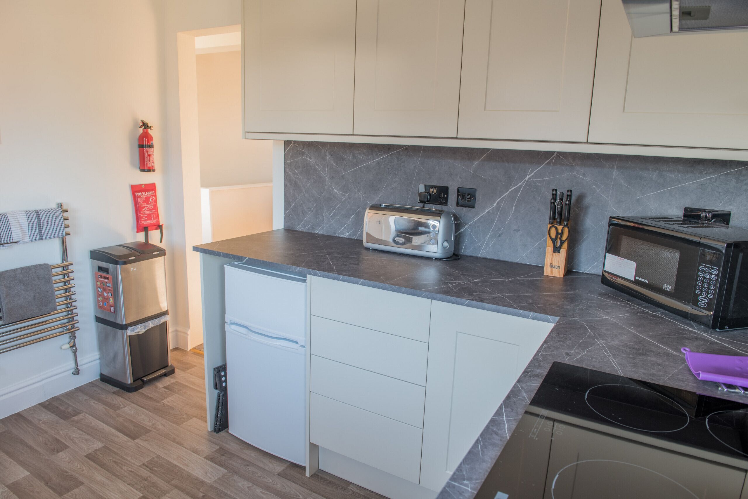 Eine kompakte Küche mit Toaster, Mikrowelle und kleinem Kühlschrank.