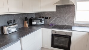 A modern kitchen with white cabinets, a microwave, a toaster, and an oven. - Toothbrush Apartments - East Ipswich - Cauldwell Ave (Ipswich)