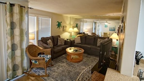 Ein Wohnzimmer mit Ecksofa, Schaukelstuhl, Couchtisch und Fernseher.