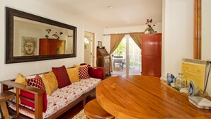 A cozy room with a wooden sofa, a round wooden table, and a large mirror on the wall. - Luxury, AC, Adjacent to Acres of State Oceanfront Land (Pahoa)