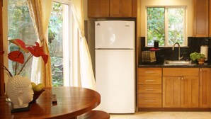 A kitchen with wooden cabinets, a white refrigerator, a sink, and a window with curtains. - Luxury, AC, Adjacent to Acres of State Oceanfront Land (Pahoa)