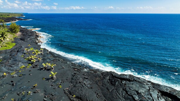 A coastal landscape with a rocky shoreline, ocean waves, and a clear sky. - Luxury, AC, Adjacent to Acres of State Oceanfront Land (Pahoa)