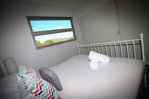 A bedroom with a bed, two windows, and a white headboard. - Pindara - Modern, 5 bedroom house with fabulous valley views! (Broke)