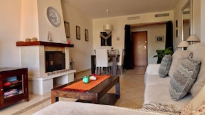 Una sala de estar con chimenea, un sofá, una mesa de centro y una zona de comedor al fondo.