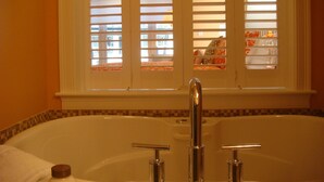Une salle de bain avec une baignoire, deux robinets et une fenêtre avec des stores.