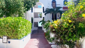 A pathway leading to a white building with blue accents and a sign indicating guest-only parking. - Beautiful & Cozy Space in Half Moon Bay Akumal (Akumal)