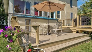 Une terrasse ensoleillée à l’arrière d’une maison, avec des meubles d’extérieur et une plante en pot.