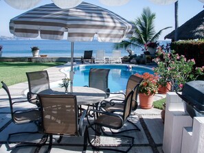 An outdoor pool area with lounge chairs, a table, and a grill. - Mexican Riviera Beach House - Manzanilllo, Playa De Oro (Club Santiago)