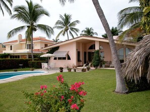 A house with a swimming pool, surrounded by palm trees and a well-maintained lawn. - Mexican Riviera Beach House - Manzanilllo, Playa De Oro (Club Santiago)