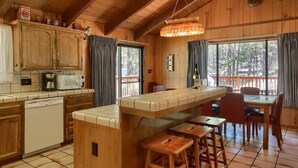 A wooden cabin interior with a kitchen, dining area, and bar. - (69) Bordentown West at The Redwoods In Yosemite (Yosemite National Park)