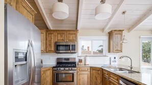 A kitchen with wooden cabinets, stainless steel appliances, and a wooden floor.