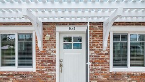 A brick building with a white door marked "831" and a porch with a colorful welcome mat.