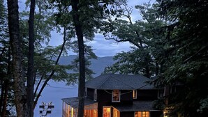 Une cabane avec une façade en verre, une terrasse en bois et une vue sur un lac.