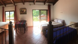 A room with a bed, a table, and a sofa. There is a painting on the wall and a window with curtains. - Apartamentos los Nazarenos PRIVATE APT 4 - heated swimming pool, jacuzzi and gym (Antigua Guatemala)