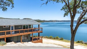 Une maison en bois à deux étages, dotée d’un balcon donnant sur un lac.