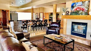 A spacious living room with a fireplace, leather sofas, a coffee table, and a dining area with chairs and a table. - Beautiful Lodge and Private 600 acre Canyon Paradise (Altamont)