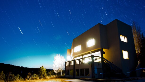 A modern building with a flat roof and multiple windows, surrounded by a grassy area and trees. - Beautiful Lodge and Private 600 acre Canyon Paradise (Altamont)