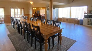 A spacious dining area with a large wooden table and chairs, a high ceiling with exposed beams, and large windows allowing natural light. - Beautiful Lodge and Private 600 acre Canyon Paradise (Altamont)