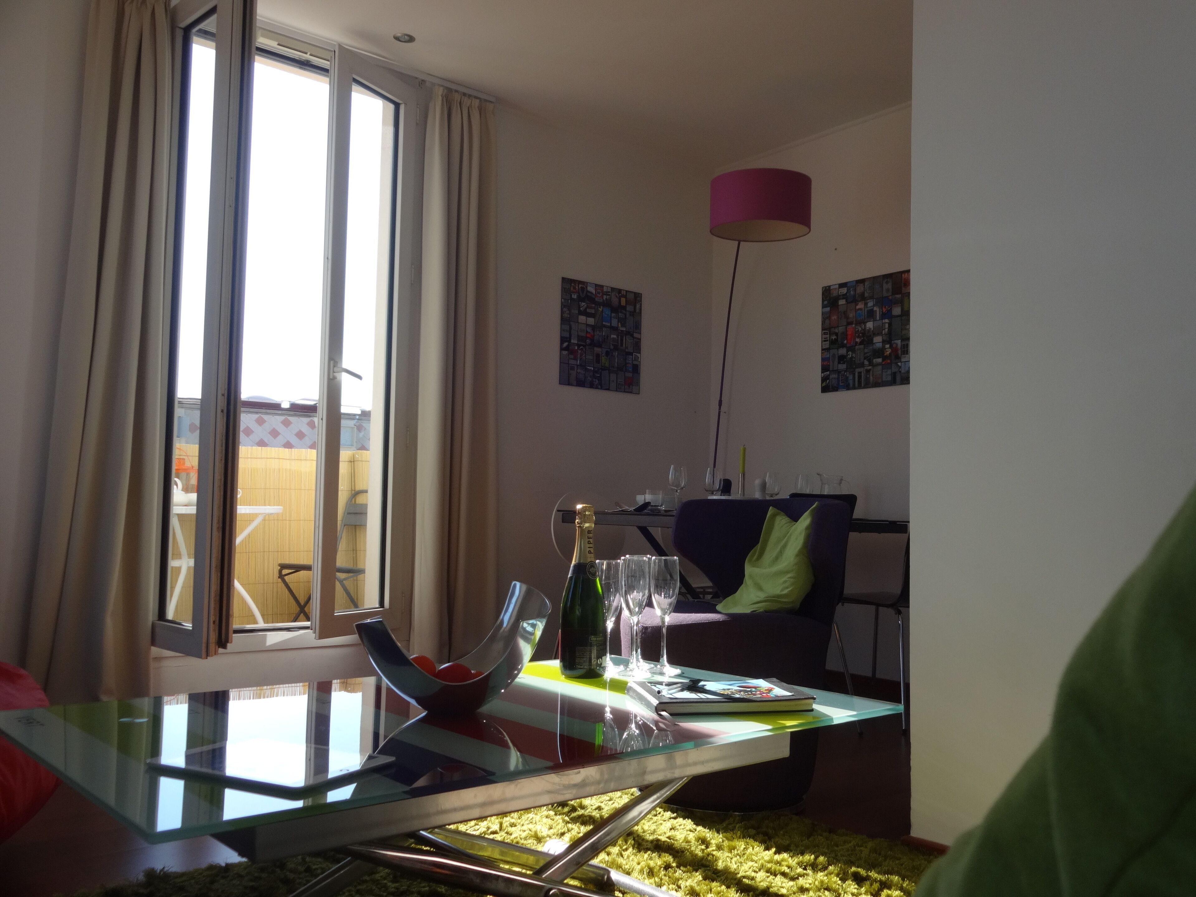 Un salon moderne avec une table en verre, un canapé et un coin repas comprenant des chaises et une table.