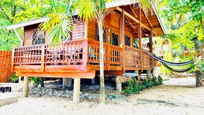 A wooden house with a balcony, surrounded by lush greenery. - Stay & Dive! Ocean front, Cozy Casita steps to the waters edge!  (Roatan, Bay Islands)
