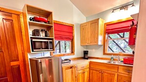 A kitchen with wooden cabinets, a stainless steel refrigerator, a microwave, and a coffee maker. - Stay & Dive! Ocean front, Cozy Casita steps to the waters edge!  (Roatan, Bay Islands)