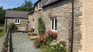 A stone house with a gravel driveway and flower beds. - Llwyn Llwyd Cottage Brecon  Group and contractor friendly. Garden. Dog friendly  (Aberyscir)