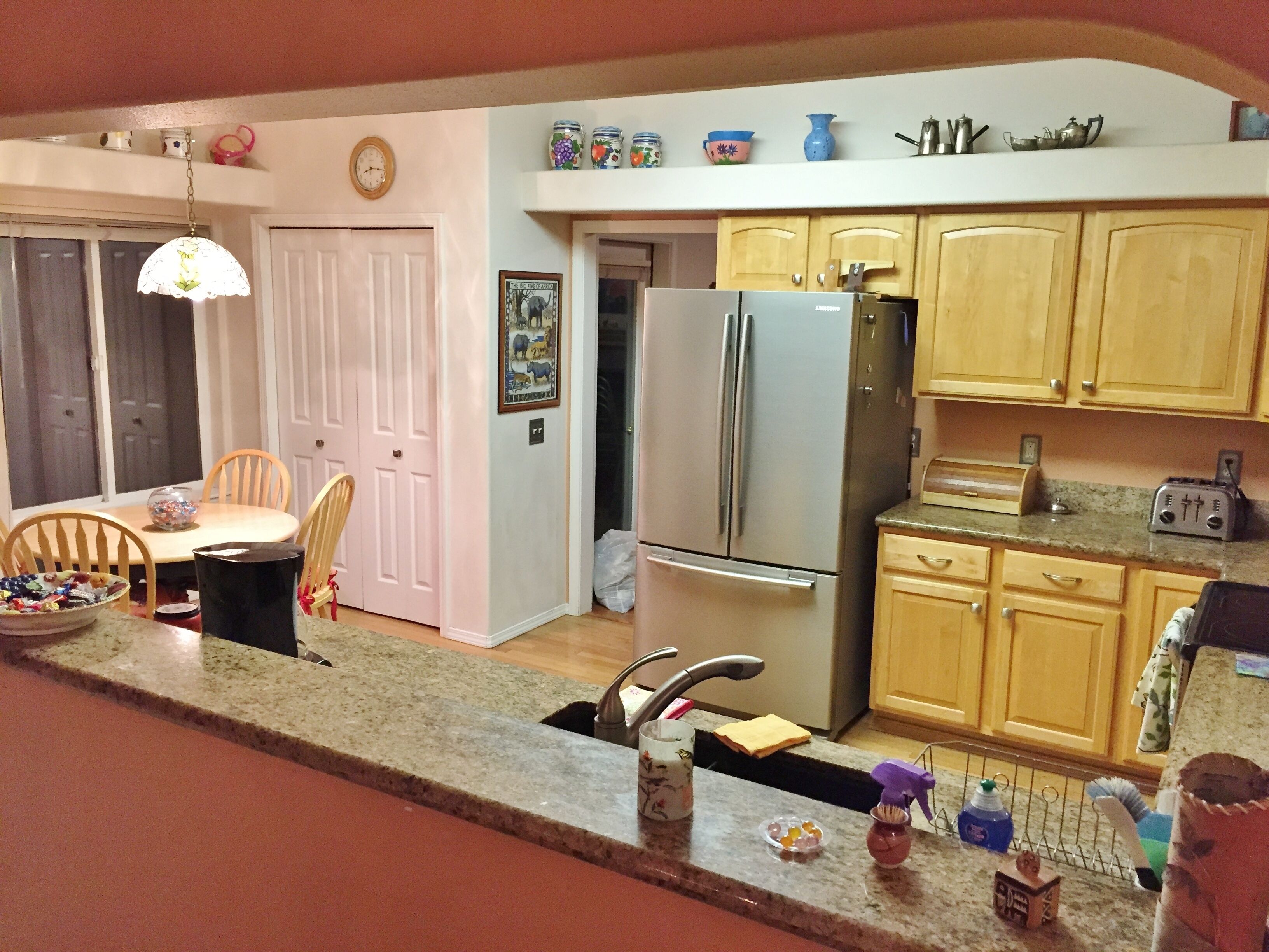 Una cocina con armarios de madera, un refrigerador de acero inoxidable, un tostador y una zona de comedor con mesa y sillas.