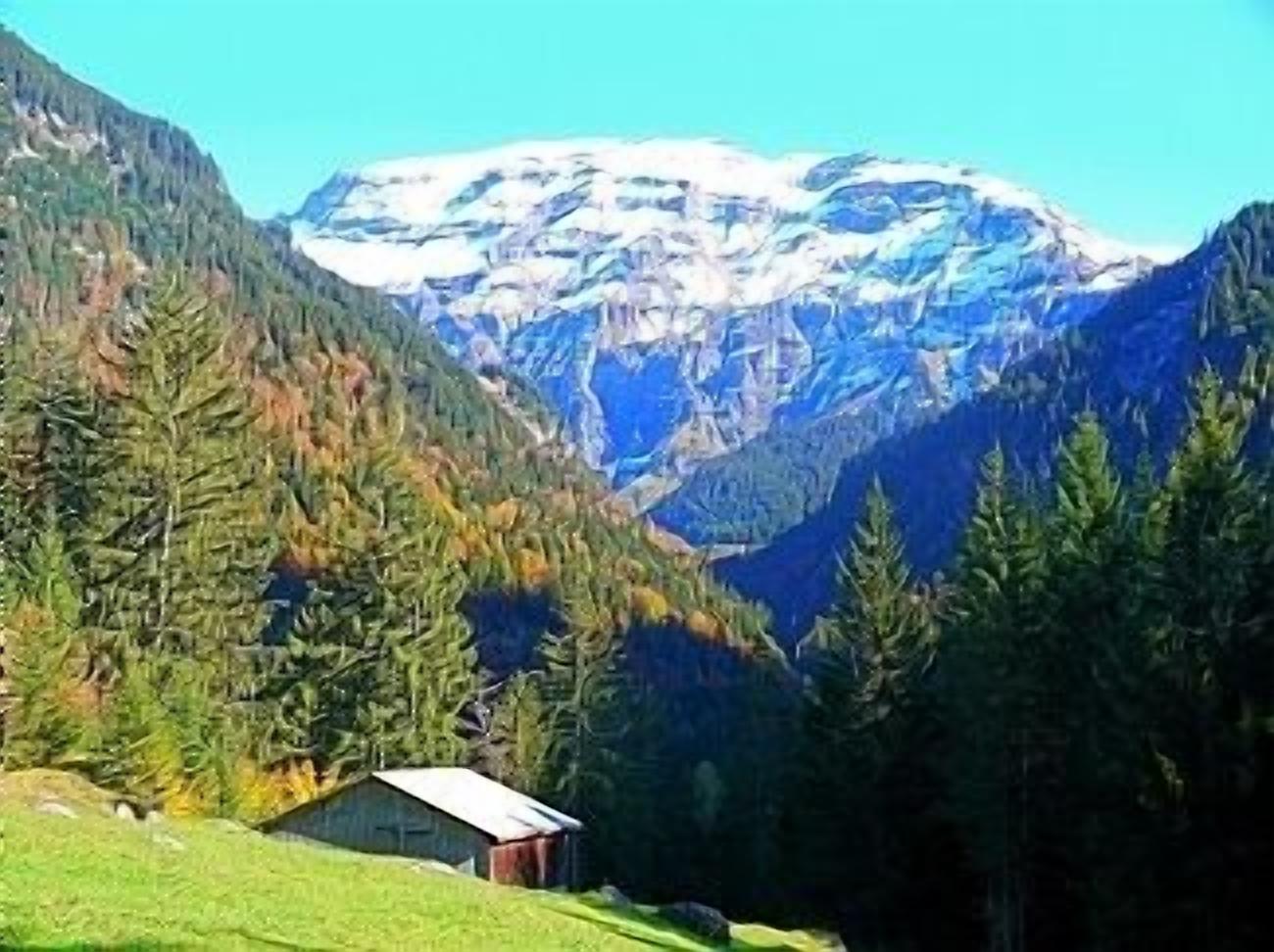 A cabin in a mountainous area with a view of snow-capped peaks.
