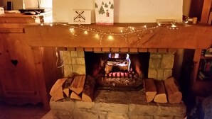 A fireplace with a stone surround, a mantel decorated with lights, and a sign above it. - Light airy Chalet - Mountain And Waterfall Views. Excellent access all Amenities (Samoëns)