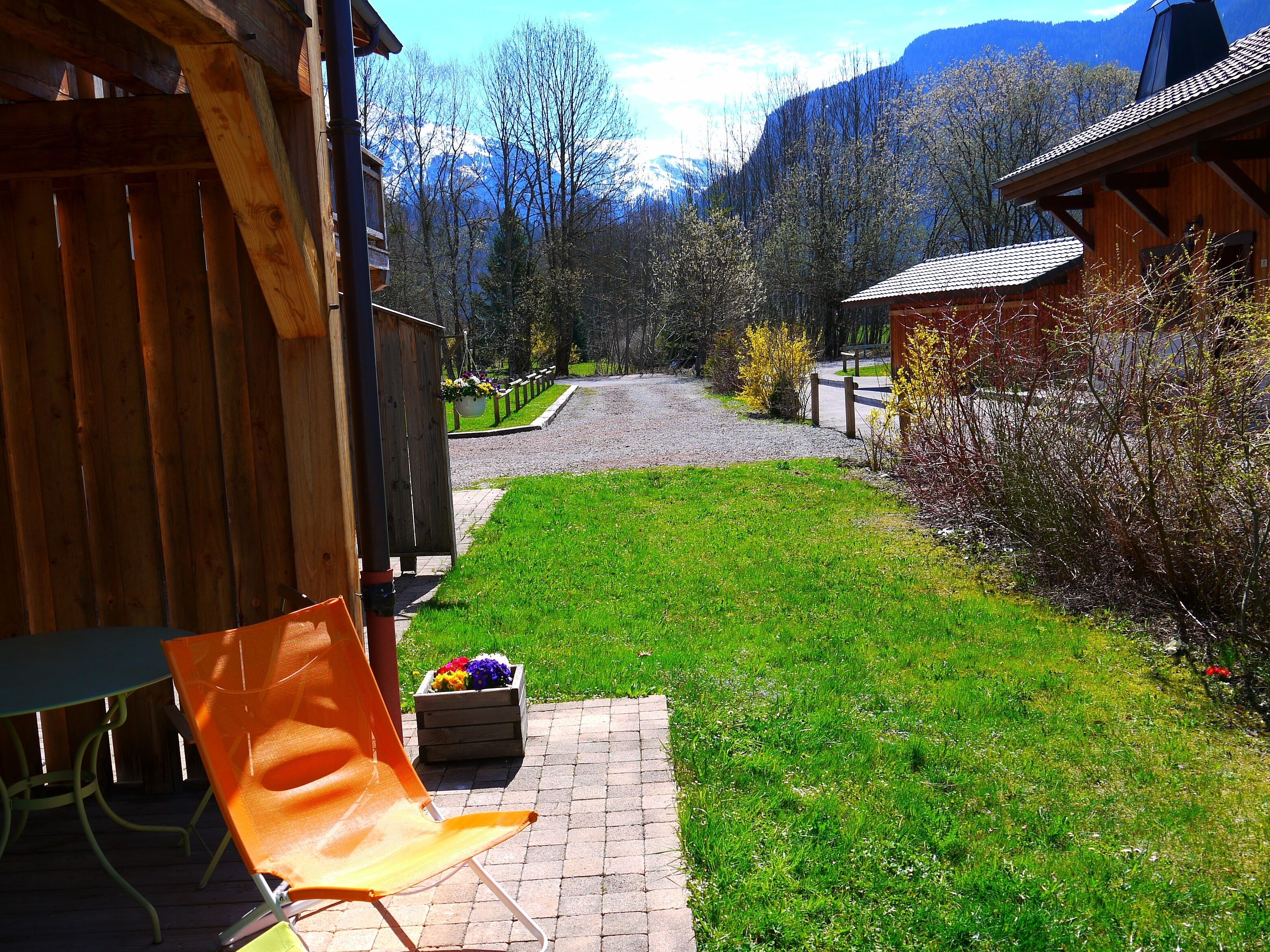 A wooden cabin with a paved path leading to a grassy area.