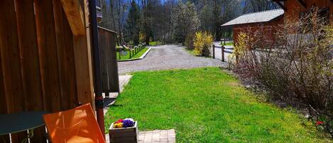 A wooden cabin with a paved path leading to a grassy area.