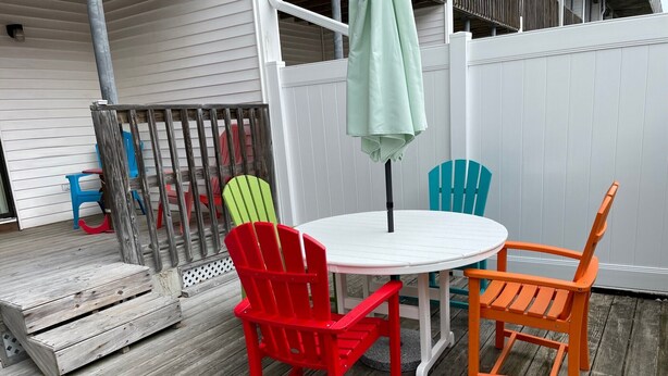 Een ronde tafel met een witte tafelblad, omringd door drie stoelen in rood, groen en oranje.