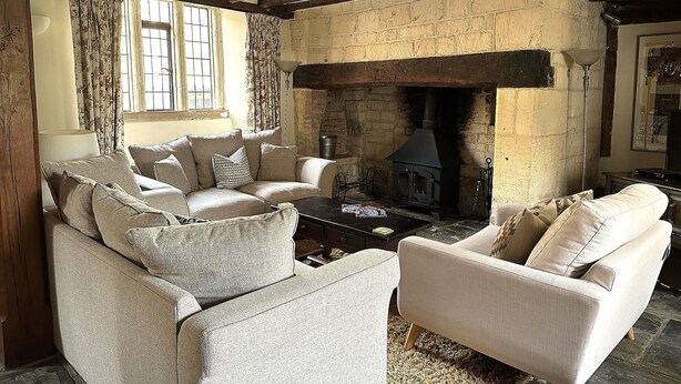 A cozy living room with a fireplace, wooden beams, and comfortable seating.