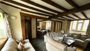 A spacious living room with a high ceiling and exposed wooden beams, furnished with sofas and a coffee table.