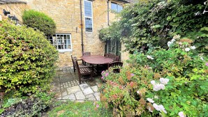 A stone building with a wooden table and chairs in a garden area.