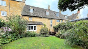 A stone house with a well-maintained garden and a small patio area.