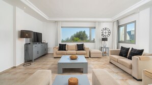 Una sala de estar moderna con un sofá gris, una mesa de centro y un televisor sobre un mueble.