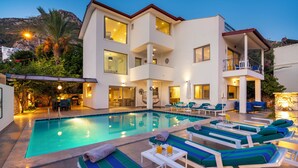 Un hotel moderno con piscina, sillas de descanso y comedor.