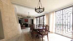 A spacious dining area with a large table, multiple chairs, and a chandelier. - Relax and enjoy breath taking ocean views from one of Tobago's premier villas! (Mount Irvine, Tobago)
