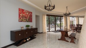 A spacious dining area with a marble floor, a wooden dining table, and chairs. There is a decorative painting on the wall and a chandelier above the table. - Relax and enjoy breath taking ocean views from one of Tobago's premier villas! (Mount Irvine, Tobago)