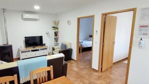 A compact living space with a dining area, a TV, a bookshelf, and a bedroom visible through an open door. - Family-friendly Cottage With Pool In Stunning Location (Alvorge)