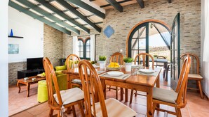 Un coin repas avec une table et des chaises en bois, un téléviseur et un mur en briques.