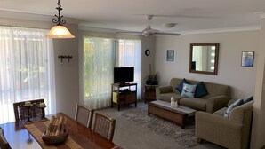 A living room with a television, sofa, and dining area with chairs and a table. - Beach Haven Villa - close to beach and breakwall (NORTH HAVEN)