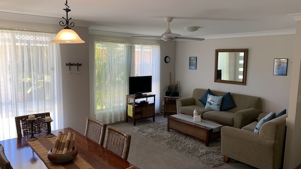 A living room with a television, sofa, and dining area with chairs and a table.