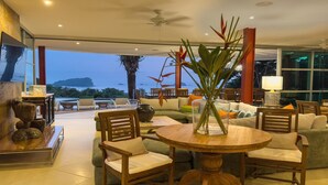 Uma sala de estar moderna com uma mesa redonda de madeira, assentos confortáveis e vista para o oceano.