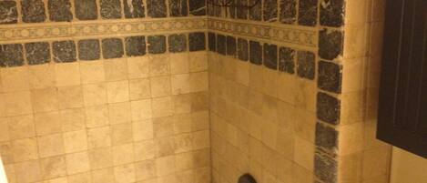 A bathroom with a bathtub, a towel rack, and a tiled wall with a decorative border.