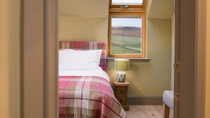 A bedroom with a bed, a nightstand, a lamp, and a window with a view of the countryside. - TIME - Charming Countryside Barn Conversion with Hot Tub & Scenic Views (Galashiels)