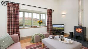 A cozy room with a sofa, a small table with a tray of cups and a coffee pot, a television, and a wood-burning stove. - TIME - Charming Countryside Barn Conversion with Hot Tub & Scenic Views (Galashiels)