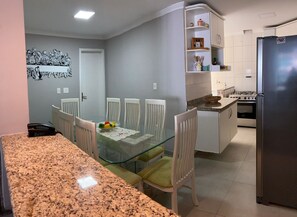 Une cuisine moderne avec un coin repas, des plans de travail en granit, des meubles blancs et un réfrigérateur.